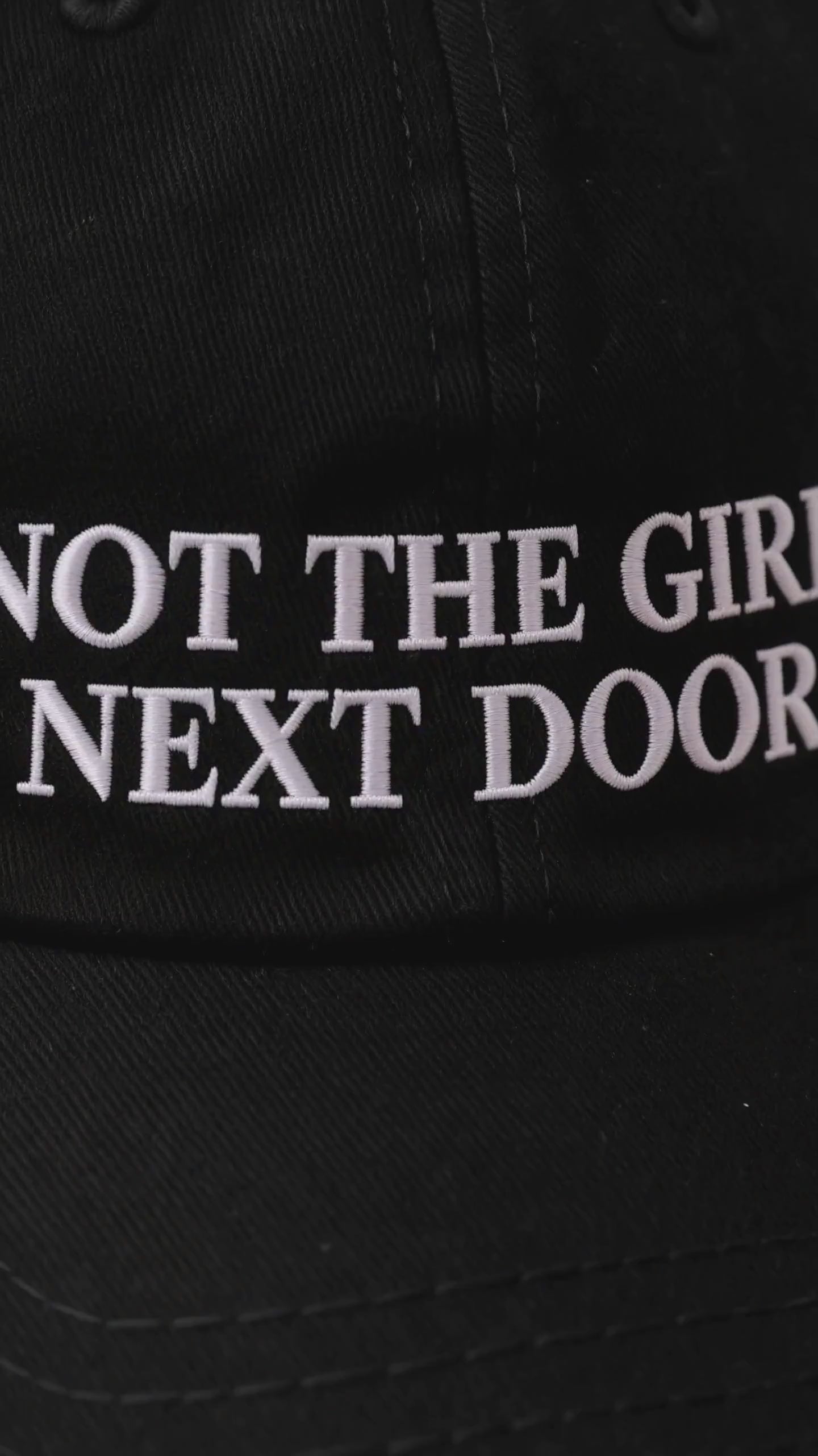 Close-up video of the embroidered Not the Girl Next Door black cap