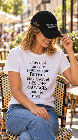 Woman at a Paris cafe wearing The Wild Geese Not the Girl Next Door black cap