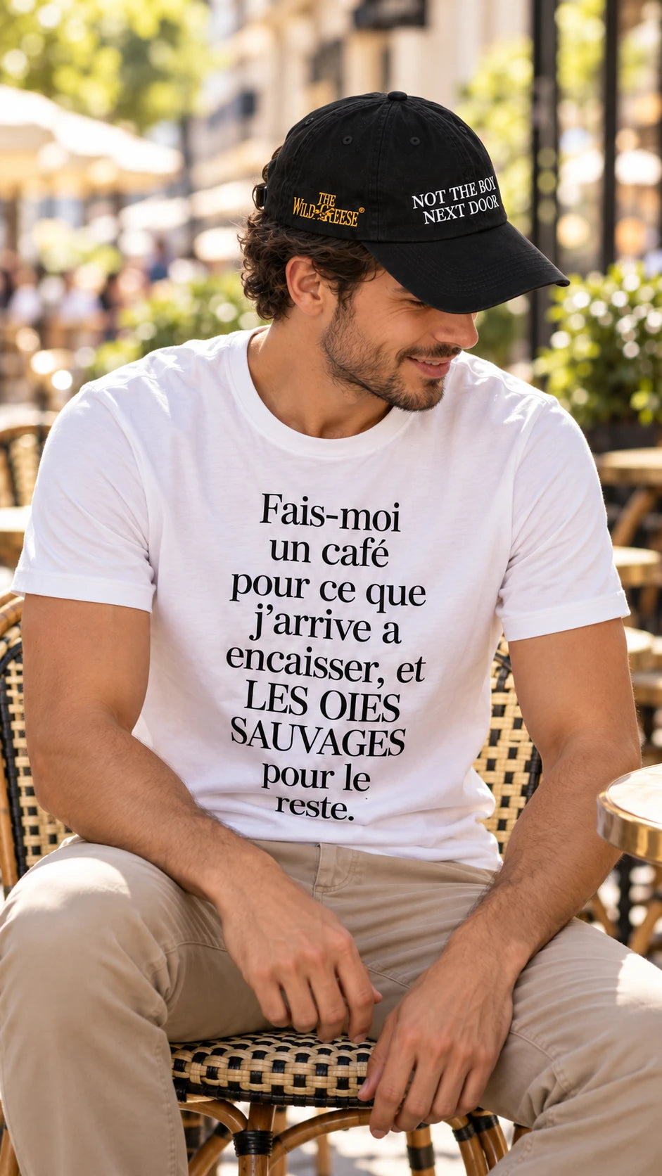 Man at a Paris cafe wearing The Wild Geese Not the Boy Next Door black cap